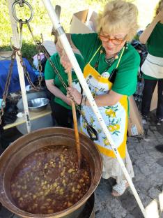 Egy nő bográcsban keveri a gulyást